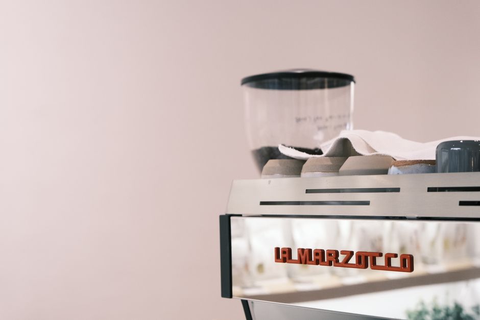 Close-up of a luxurious La Marzocco coffee machine with metallic finish in a cafe setting.