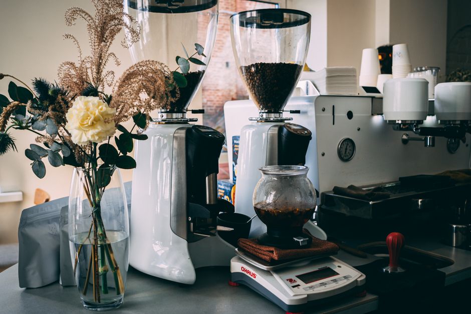 Cozy café setting with espresso machines and floral decor, ideal for coffee enthusiasts.
